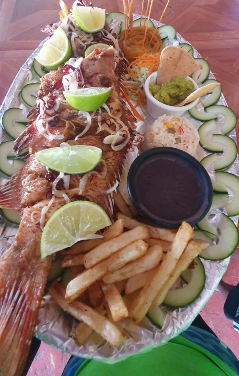 Pescado frito entero con guarniciones servido frente a la playa