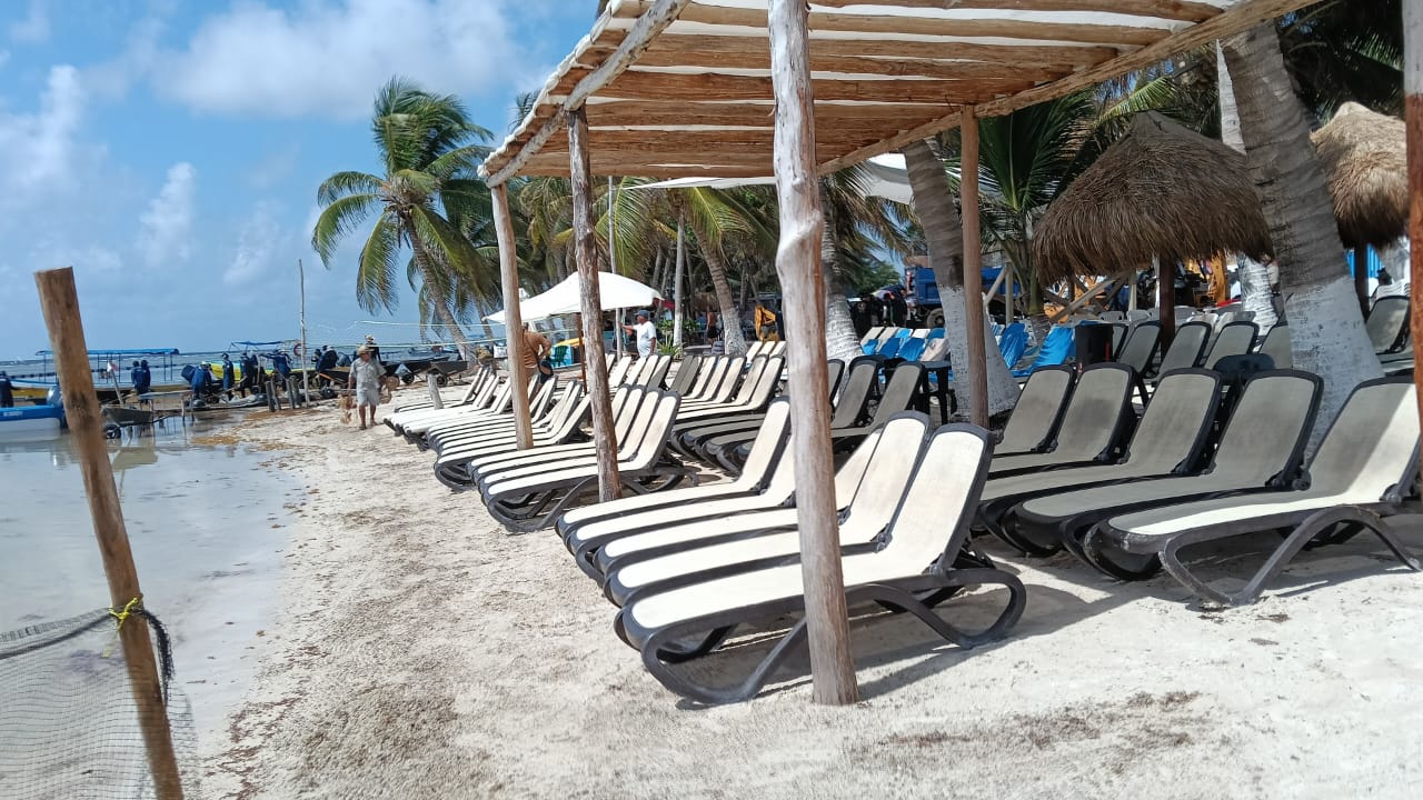 Camastros y sombrillas de madera en una playa tropical de Mahahual