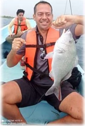Turista sonriendo con un pez capturado en el tour de pesca de altura